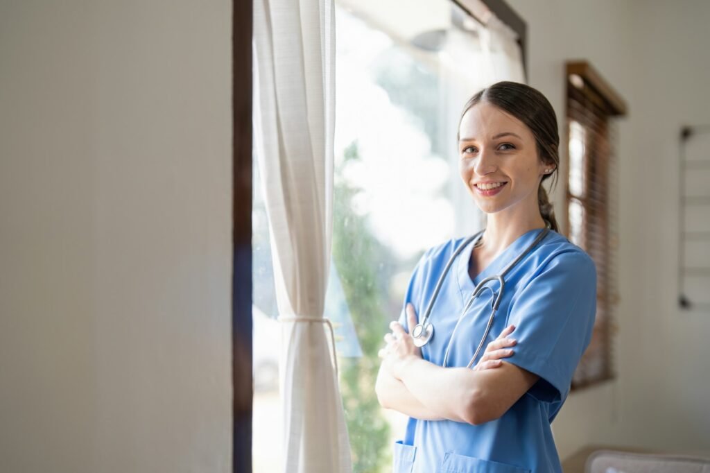 Portrait of a friendly female doctor or nurse wearing blue scrubs uniform and stethoscope, with